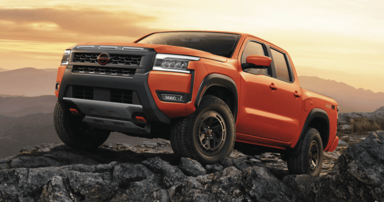 orange Nissan Frontier truck off-roading on rocks with sunset in background